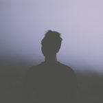 Silhouetted man standing in a misty landscape, creating a serene and introspective atmosphere.
